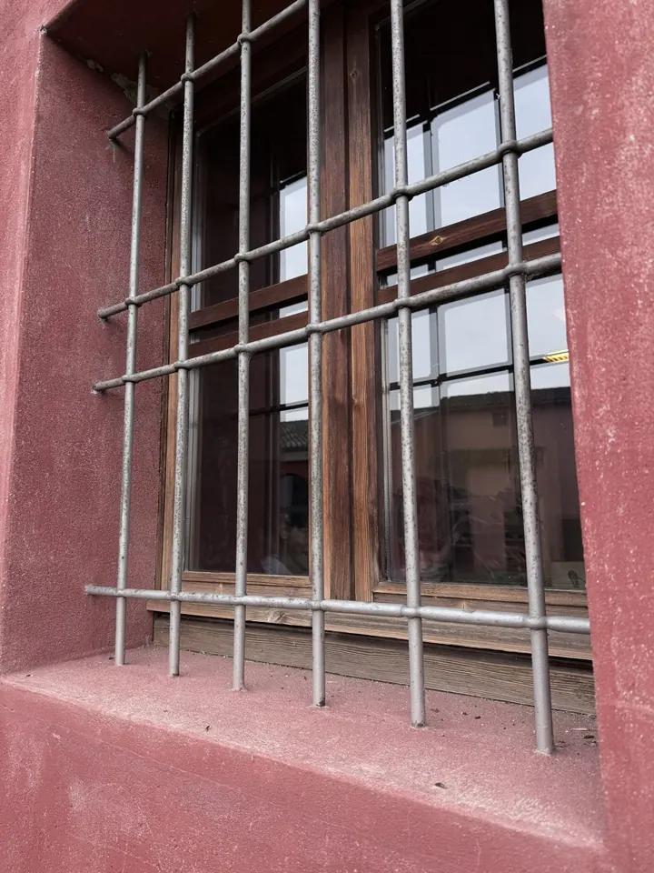 Una finestra con l’inferriata nella facciata rossa del museo