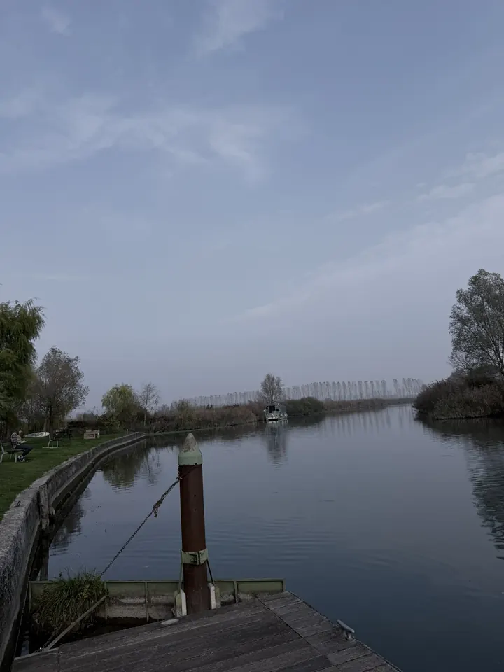 Il Mincio visto dal pontile davanti al museo, con le sponde alberate e il cielo coperto