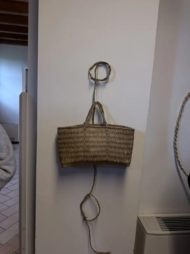 Una sporta di paglia intrecciata appesa al muro con una corda