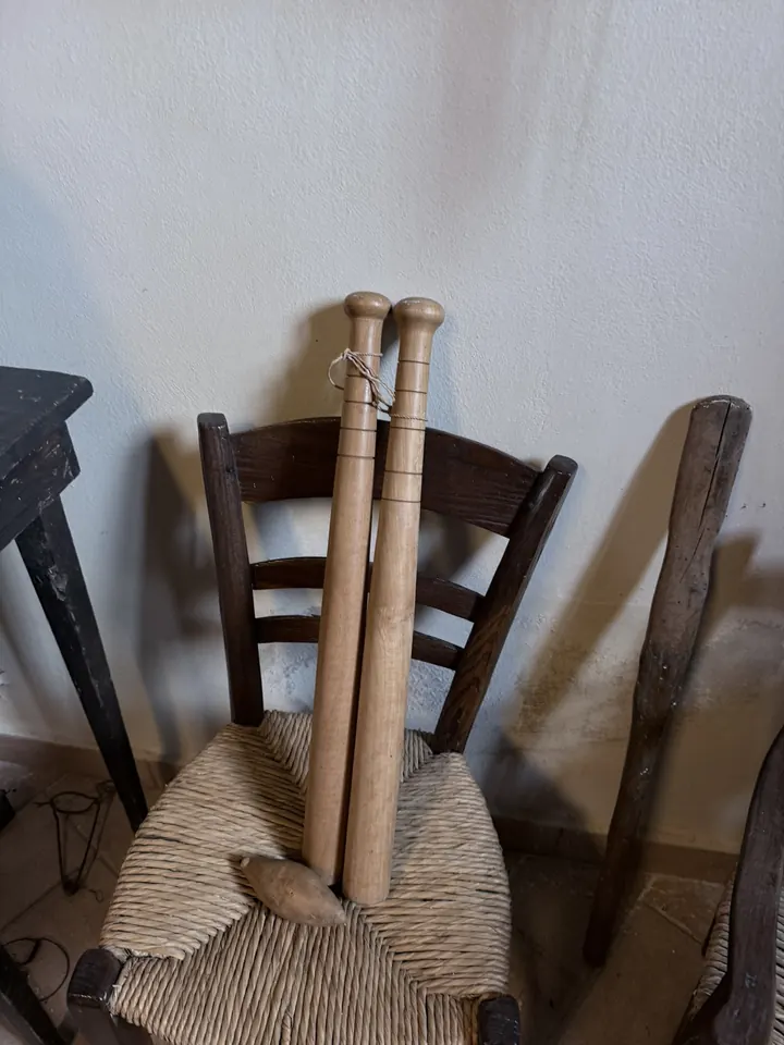Due attrezzi di legno torniti appoggiati a una sedia impagliata