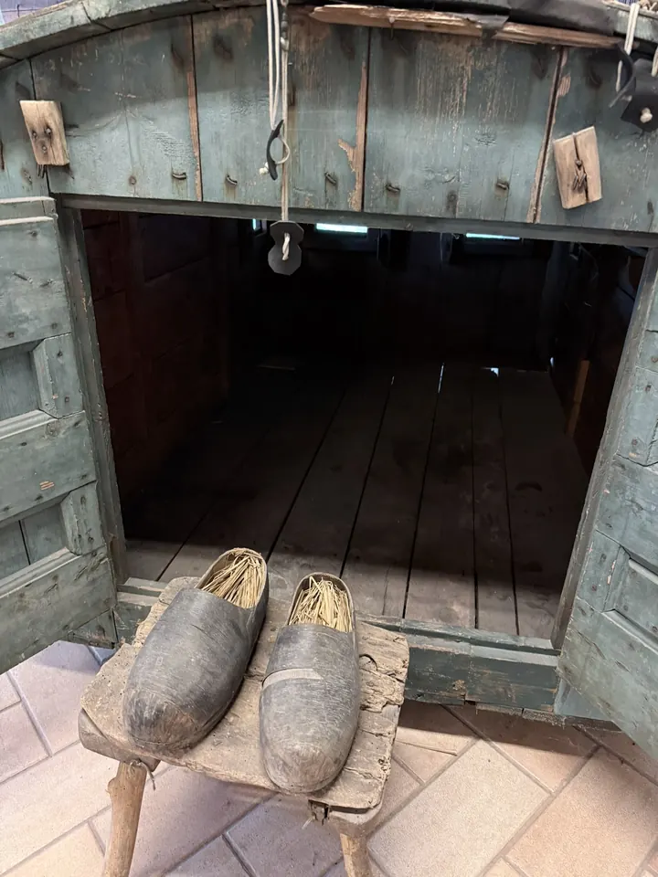 Due zoccoli di legno su uno sgabello davanti a una capanna di tavole