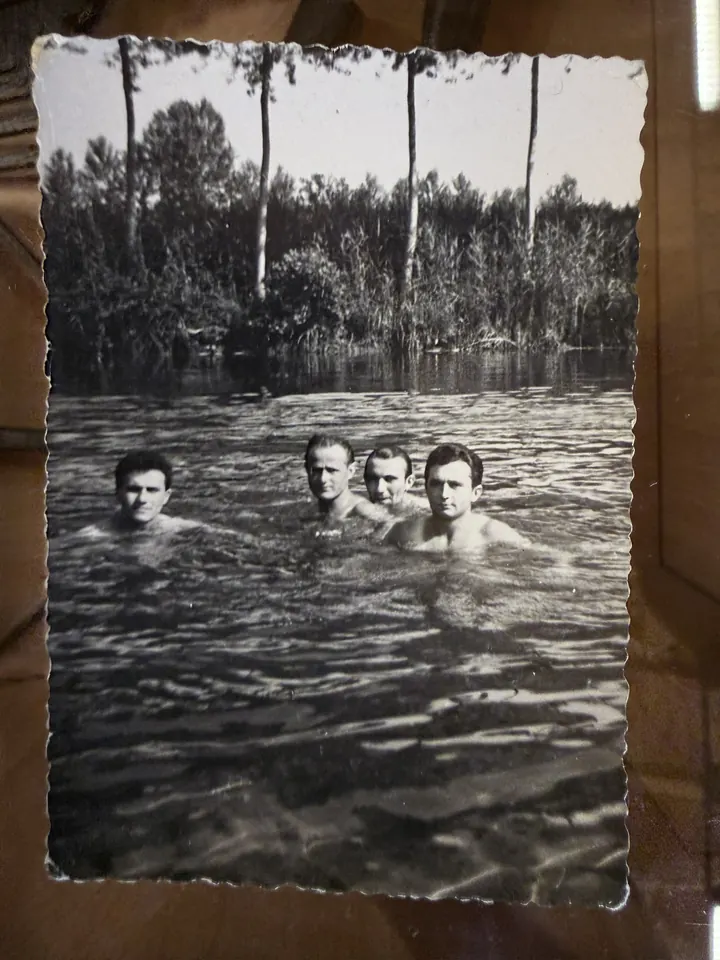 Una fotografia d’epoca in bianco e nero di quattro ragazzi che fanno il bagno nel fiume