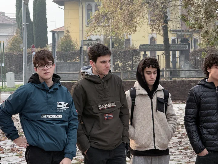 Quattro compagni di classe in piedi sulla piazza, con giacche e felpe invernali