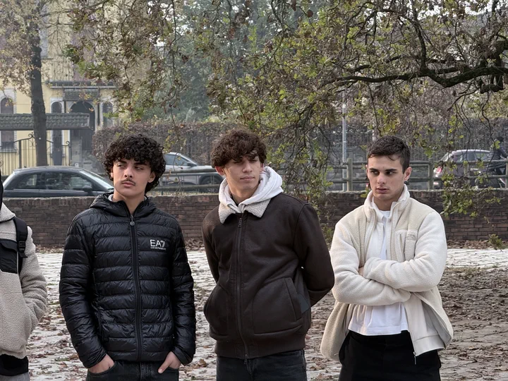 Tre compagni di classe con le mani in tasca sulla piazza coperta di foglie