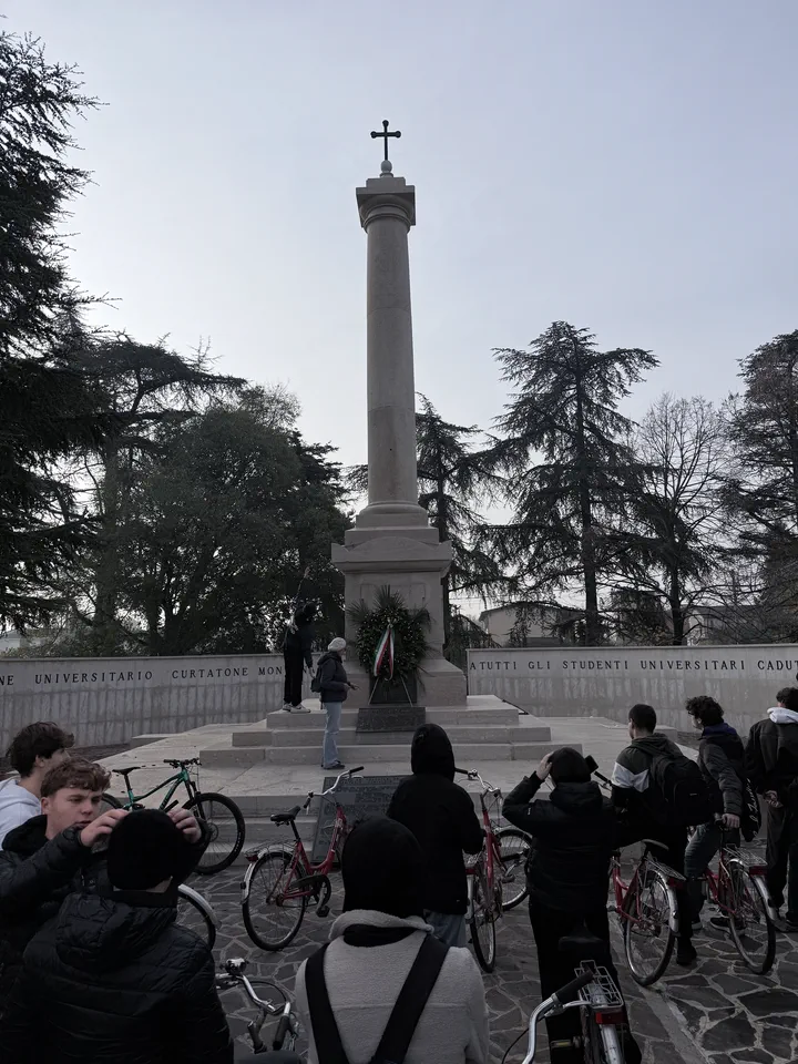 I compagni con le biciclette davanti all’obelisco del monumento ai caduti, con la croce in cima
