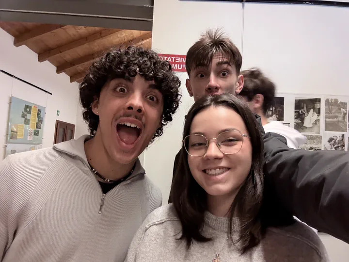 Autoscatto di tre compagni di classe sorridenti nella sala del museo