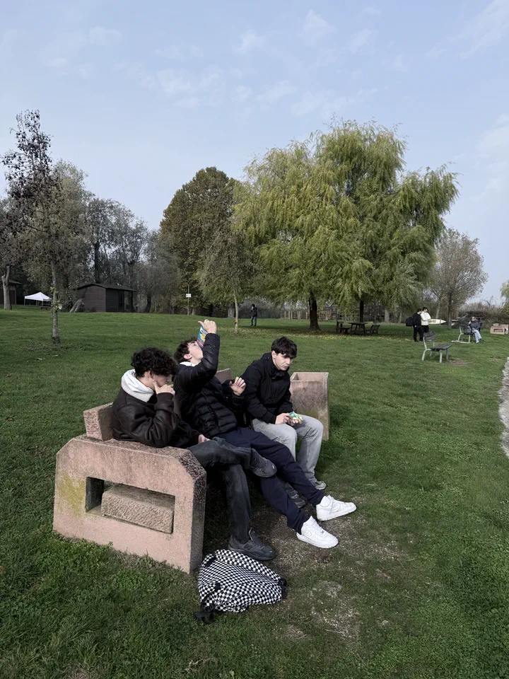 Tre compagni di classe seduti su una panchina di pietra nel prato del museo